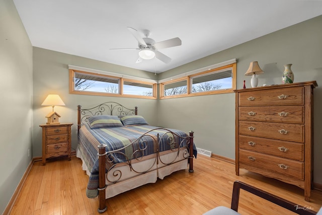 bedroom featuring visible vents, a ceiling fan, light wood-style flooring, and baseboards