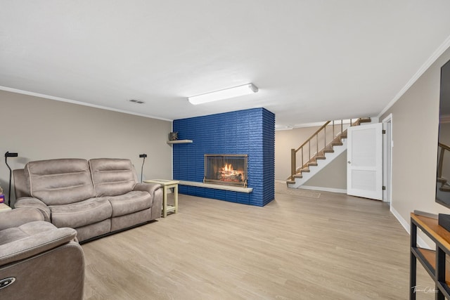 living area featuring visible vents, stairway, a fireplace, and crown molding