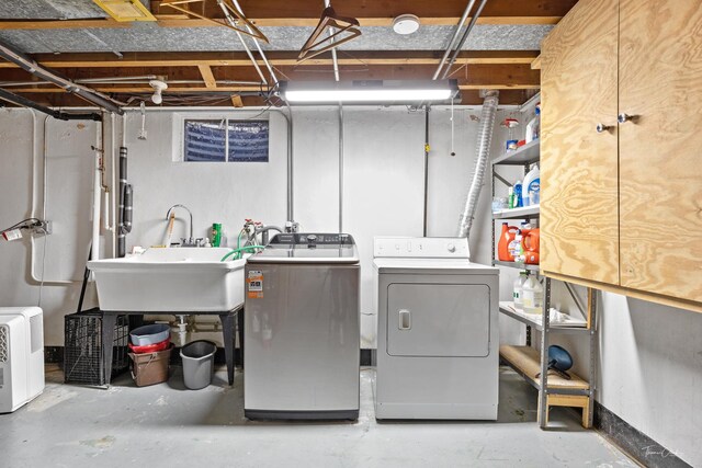 clothes washing area featuring separate washer and dryer, a sink, and laundry area