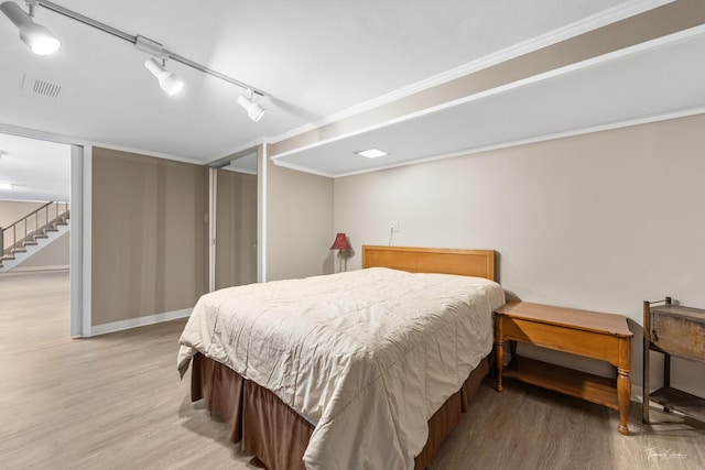 bedroom featuring visible vents, rail lighting, light wood-style flooring, and baseboards