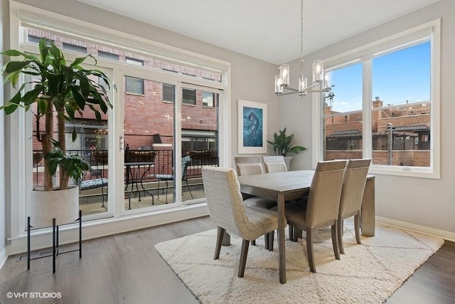 dining room with baseboards, an inviting chandelier, and wood finished floors