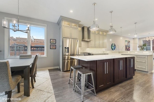kitchen featuring a notable chandelier, light countertops, dark wood finished floors, wall chimney exhaust hood, and stainless steel refrigerator with ice dispenser