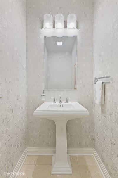 bathroom featuring tile patterned flooring, a sink, and baseboards