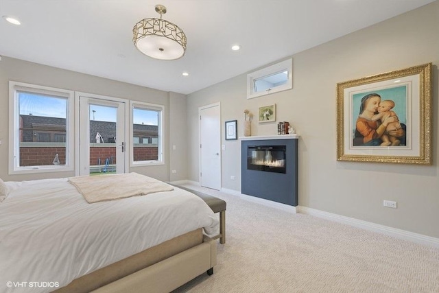 bedroom featuring baseboards, recessed lighting, a glass covered fireplace, and light colored carpet