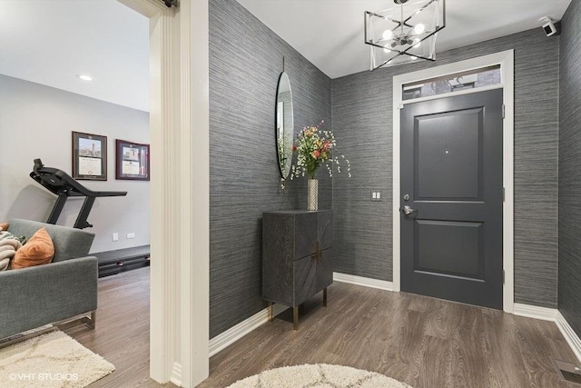 entryway featuring baseboards, wood finished floors, and a notable chandelier