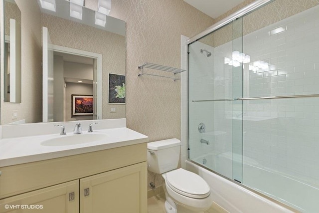 bathroom featuring toilet, bath / shower combo with glass door, and vanity