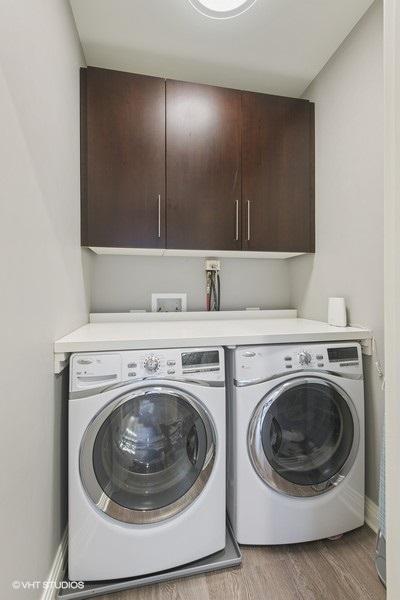washroom featuring cabinet space, independent washer and dryer, baseboards, and light wood-style floors