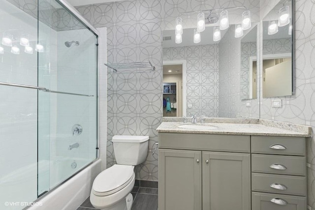 bathroom with toilet, bath / shower combo with glass door, and vanity