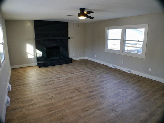 unfurnished living room featuring a ceiling fan, visible vents, wood finished floors, and baseboards