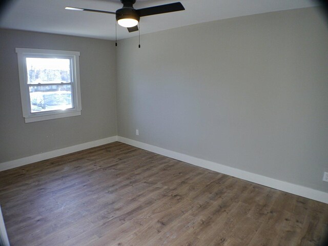 empty room with baseboards, wood finished floors, and ceiling fan