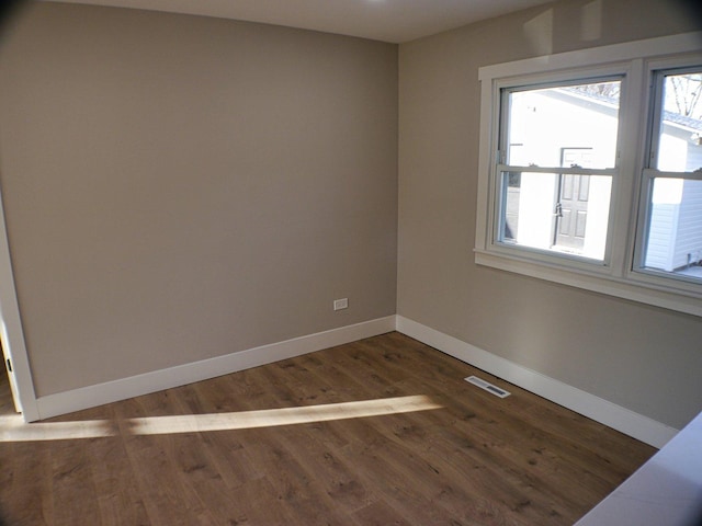 empty room featuring visible vents, wood finished floors, and baseboards