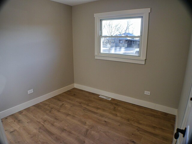 unfurnished room with baseboards, visible vents, and wood finished floors