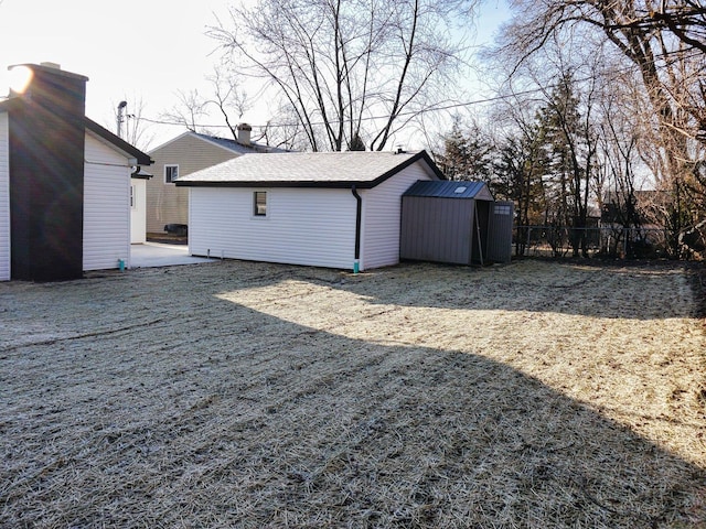 view of yard featuring fence, an outdoor structure, and a storage shed