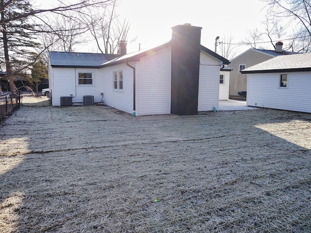 rear view of house with a chimney, fence, and central air condition unit