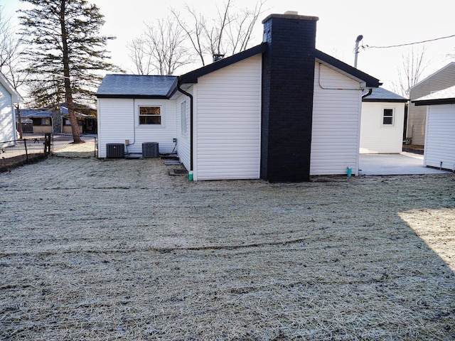 rear view of property featuring a chimney, fence, a patio area, and central air condition unit
