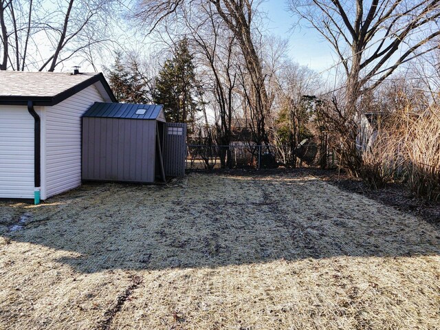 view of yard with fence, a shed, and an outbuilding