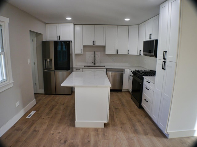 kitchen featuring appliances with stainless steel finishes, baseboards, white cabinets, and a sink