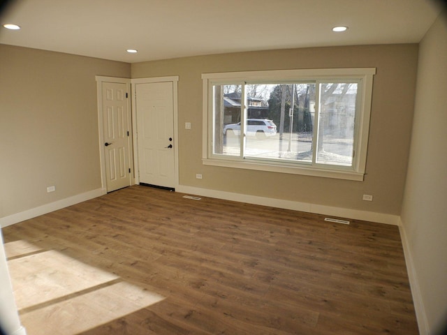 empty room with baseboards, visible vents, and wood finished floors