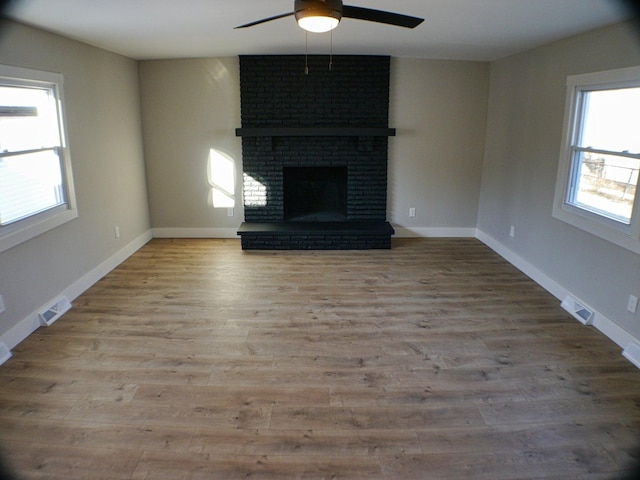 unfurnished living room with a ceiling fan, visible vents, and a wealth of natural light
