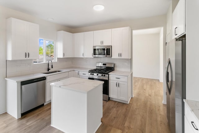 kitchen with a sink, tasteful backsplash, stainless steel appliances, and light wood finished floors