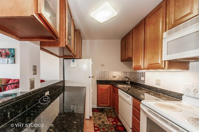 7061 N Kedzie Ave Unit 1409, Chicago, IL 60645 - kitchen featuring dark stone counters, tasteful backsplash, glass insert cabinets, a sink, and white appliances
