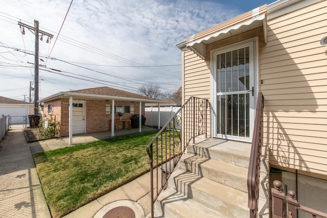 7313 W Howard Ave, Chicago, IL 60631 - view of exterior entry featuring fence, a patio area, a lawn, and brick siding