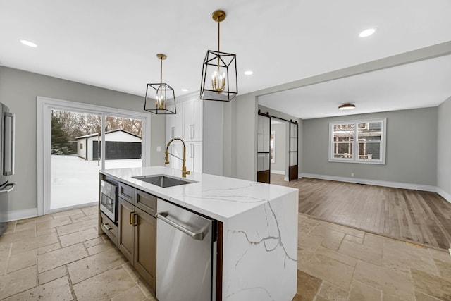 kitchen with stone tile floors, a sink, a barn door, stainless steel appliances, and recessed lighting