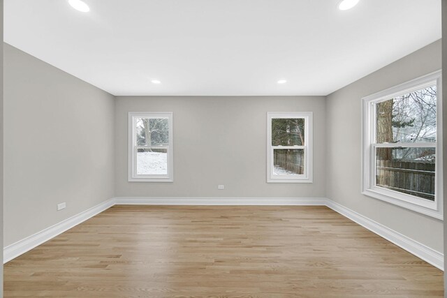 unfurnished room with a healthy amount of sunlight, light wood-style flooring, and baseboards