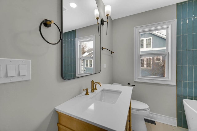 full bathroom featuring a bathing tub, toilet, vanity, baseboards, and visible vents