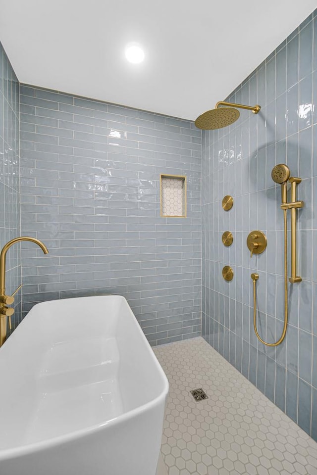 bathroom featuring tile walls, a sink, tiled shower, and tile patterned floors