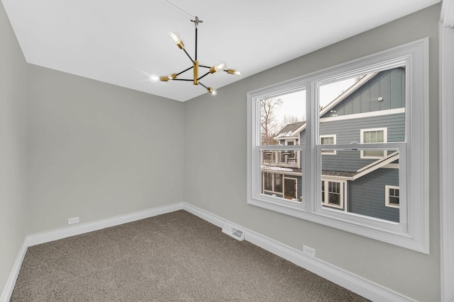 spare room featuring a chandelier, visible vents, carpet, and baseboards