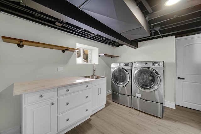 washroom featuring washer and dryer, a sink, light wood-style flooring, and baseboards