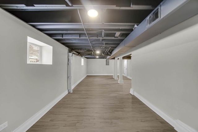 basement featuring visible vents, wood finished floors, and baseboards