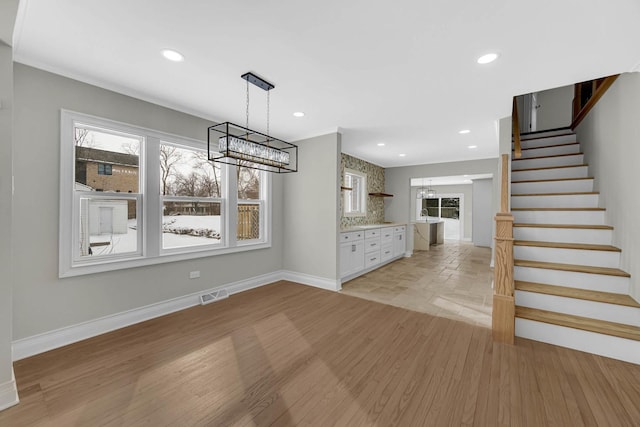 unfurnished dining area featuring stairway, visible vents, baseboards, an inviting chandelier, and recessed lighting