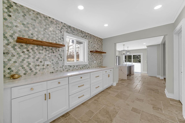 kitchen with a wealth of natural light, ornamental molding, open shelves, and white cabinetry
