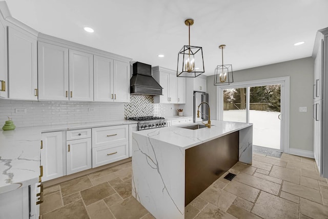 kitchen with stone tile flooring, decorative backsplash, premium range hood, and a sink