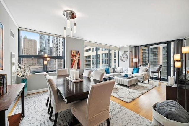 dining room featuring visible vents, a view of city, crown molding, wood finished floors, and a wall of windows
