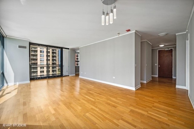 unfurnished living room with light wood-style floors, baseboards, crown molding, and visible vents