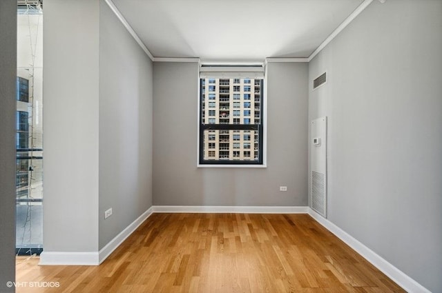 unfurnished room with baseboards, visible vents, ornamental molding, and wood finished floors