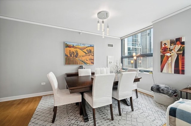 dining area with baseboards, crown molding, wood finished floors, and visible vents