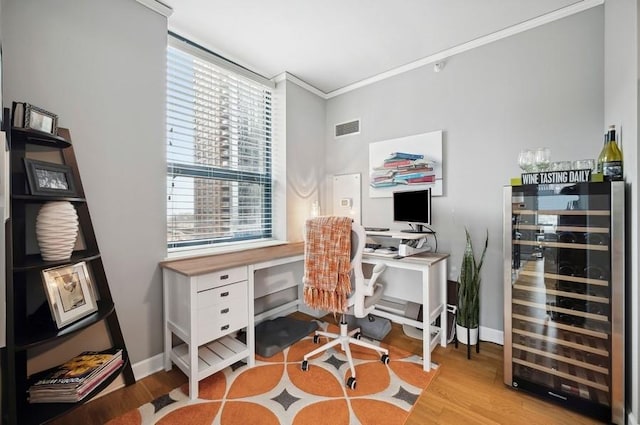 office area with crown molding, beverage cooler, visible vents, and wood finished floors