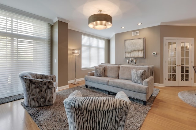 living room with visible vents, french doors, baseboards, ornamental molding, and wood finished floors