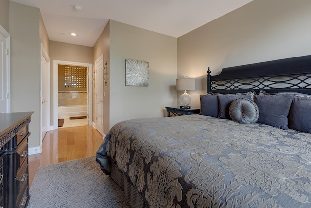 bedroom with baseboards, recessed lighting, wood finished floors, and connected bathroom