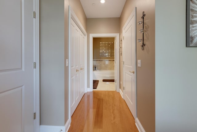 hallway with baseboards and light wood-style floors