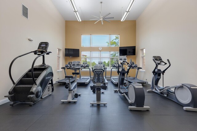 gym featuring a high ceiling, a ceiling fan, visible vents, and baseboards
