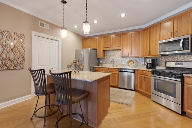 kitchen with stainless steel appliances, decorative backsplash, a kitchen bar, visible vents, and light wood-style flooring