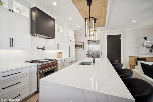 kitchen featuring wall chimney range hood, decorative backsplash, a sink, ornamental molding, and high quality appliances