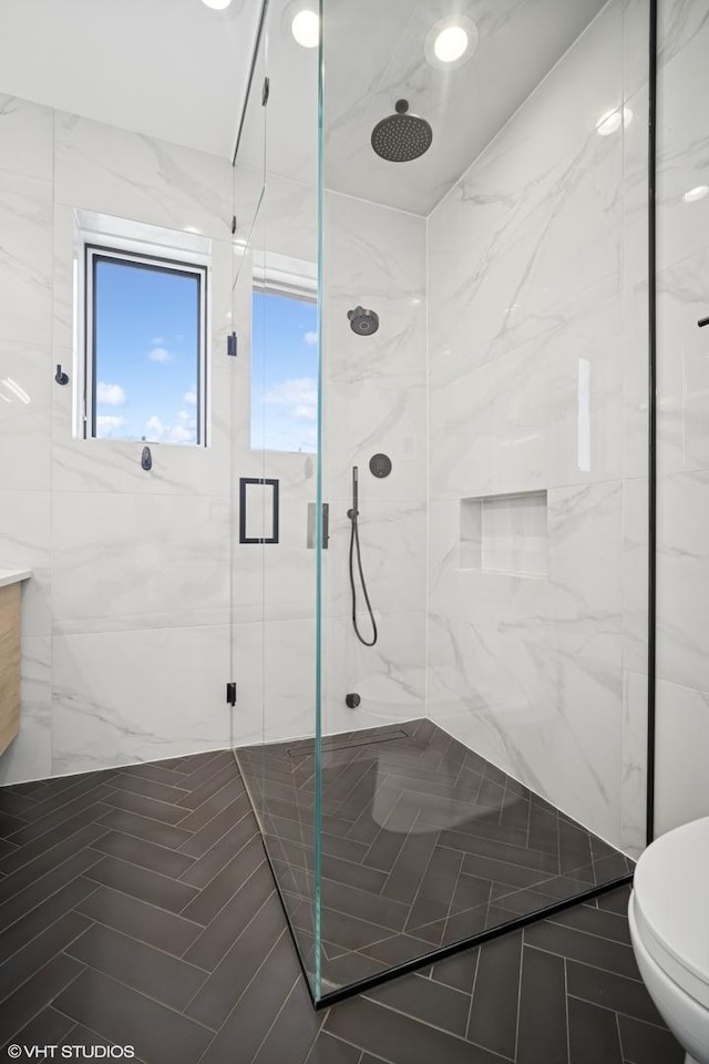 full bath featuring vanity, toilet, and a marble finish shower