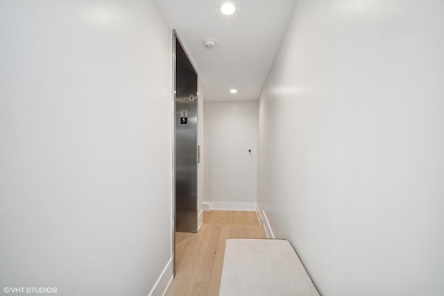 corridor featuring baseboards, recessed lighting, and light wood finished floors