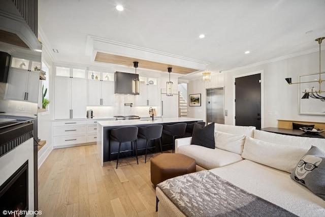 living area with light wood-style floors, recessed lighting, ornamental molding, and stairs